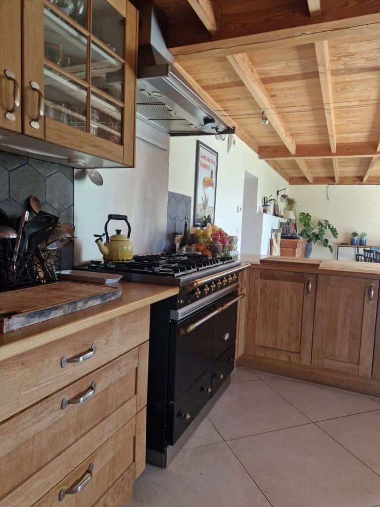 Une cuisine chaleureuse et entièrement équipée avec des meubles en bois et un grand piano de cuisson