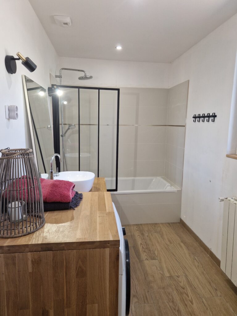 Une salle de bain moderne et chaleureuse avec baignoire, douche, meuble en bois élégant.