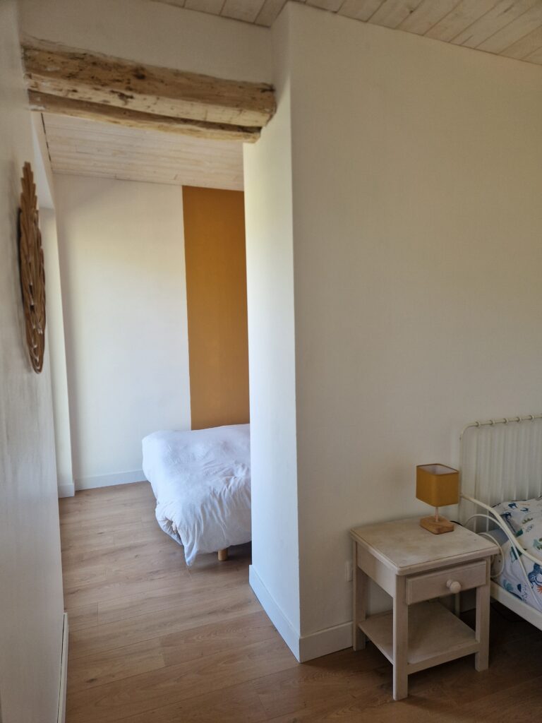Cette chambre lumineuse au parquet chaleureux dévoile un second espace nuit confortable, idéal pour un séjour en famille.