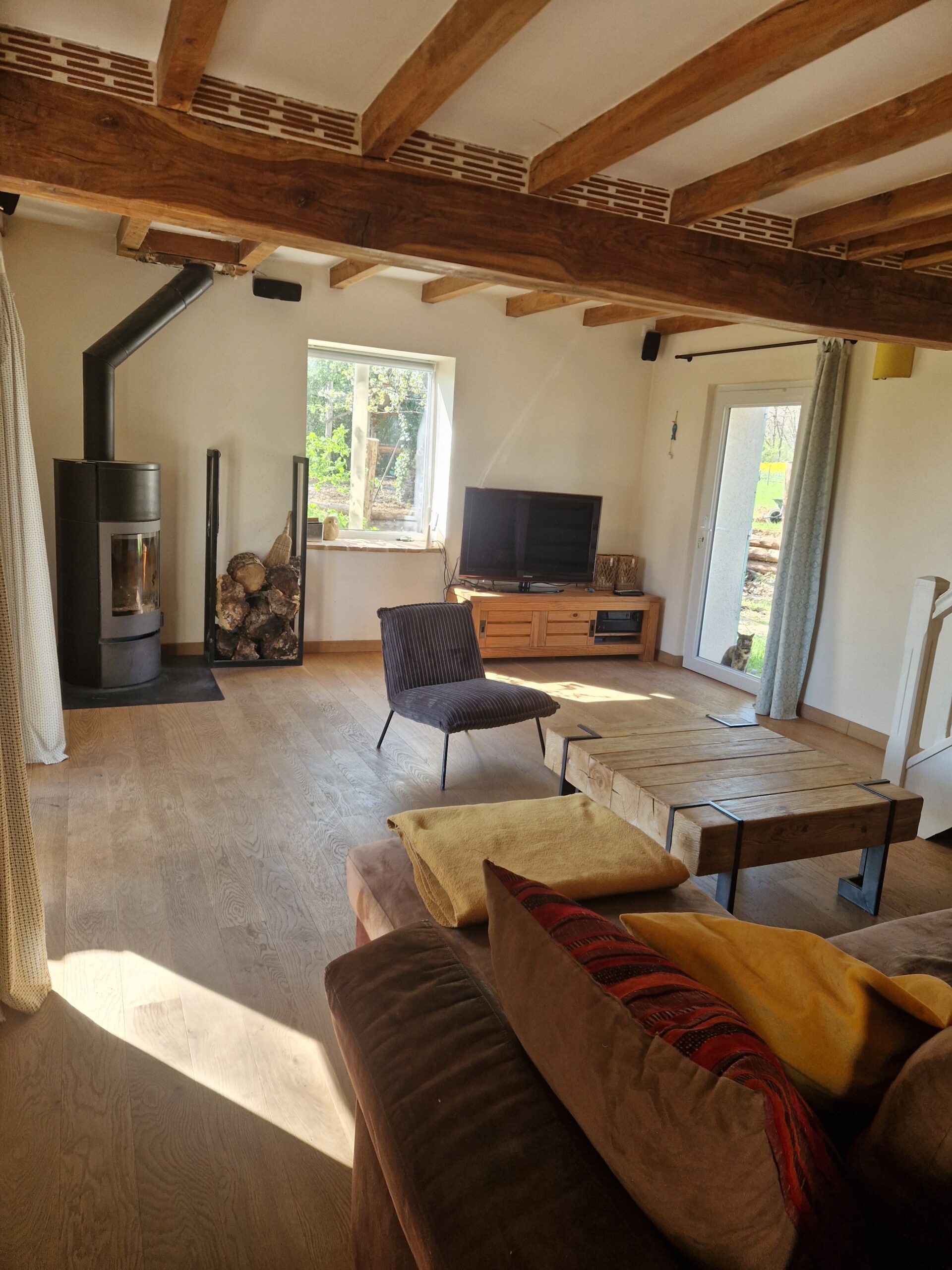 Salon chaleureux du Mas Crudel avec poêle à bois et poutres apparentes